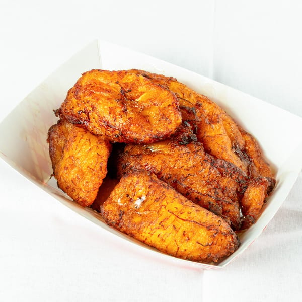 A white paper tray filled with several pieces of golden-brown fried plantains, a Venezuelan side dish.